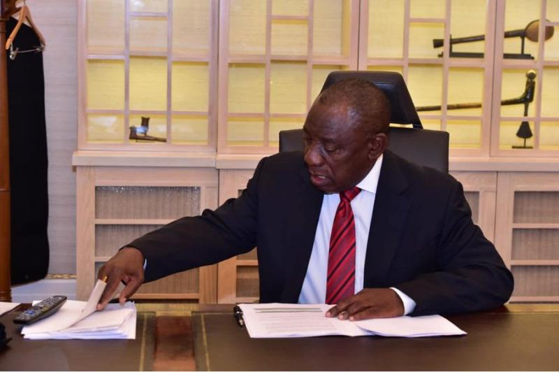 Cyril Ramaphosa seated at a desk with papers