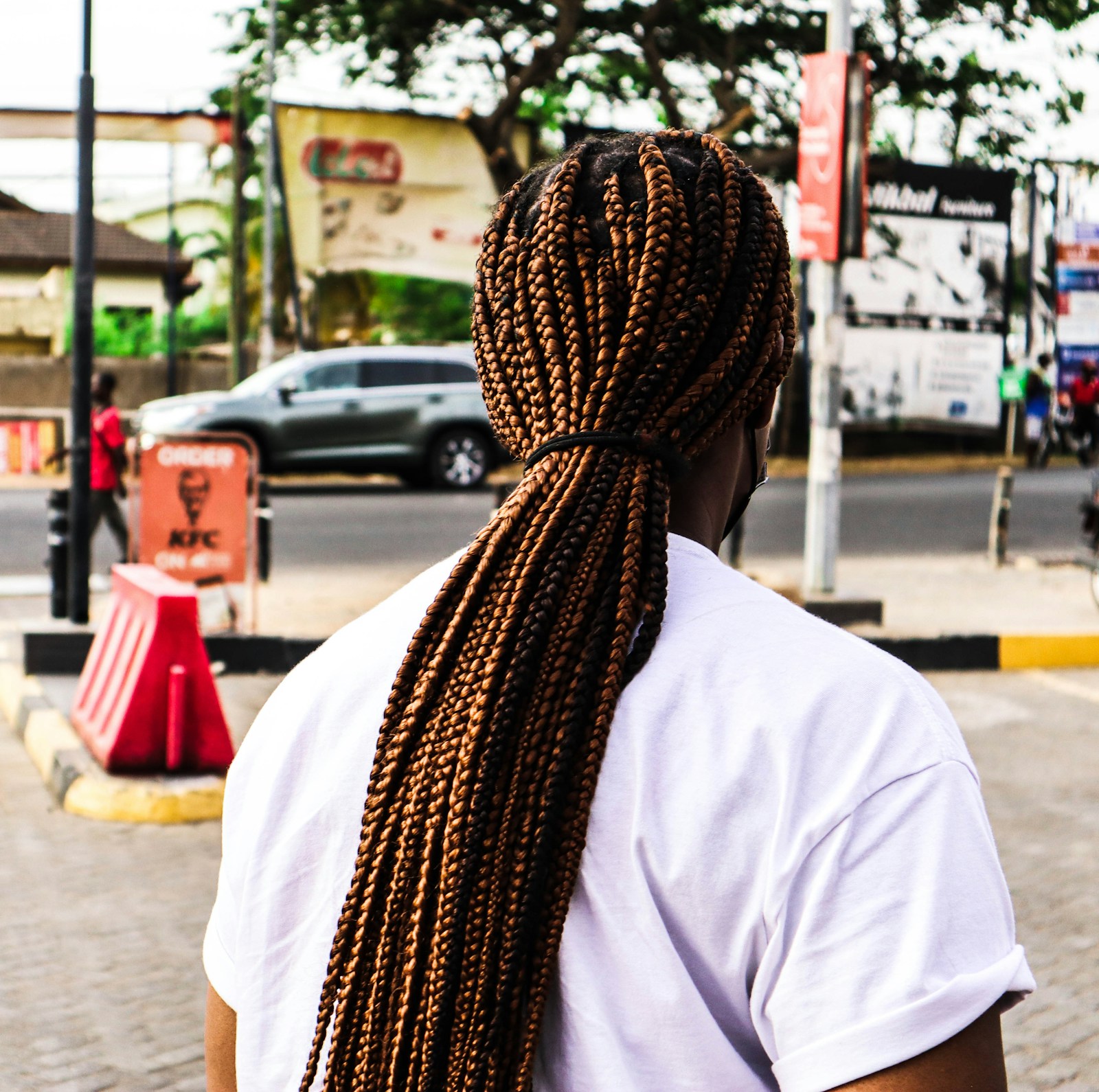 Rear view of a woman wearing long brown braids on a street in Accra