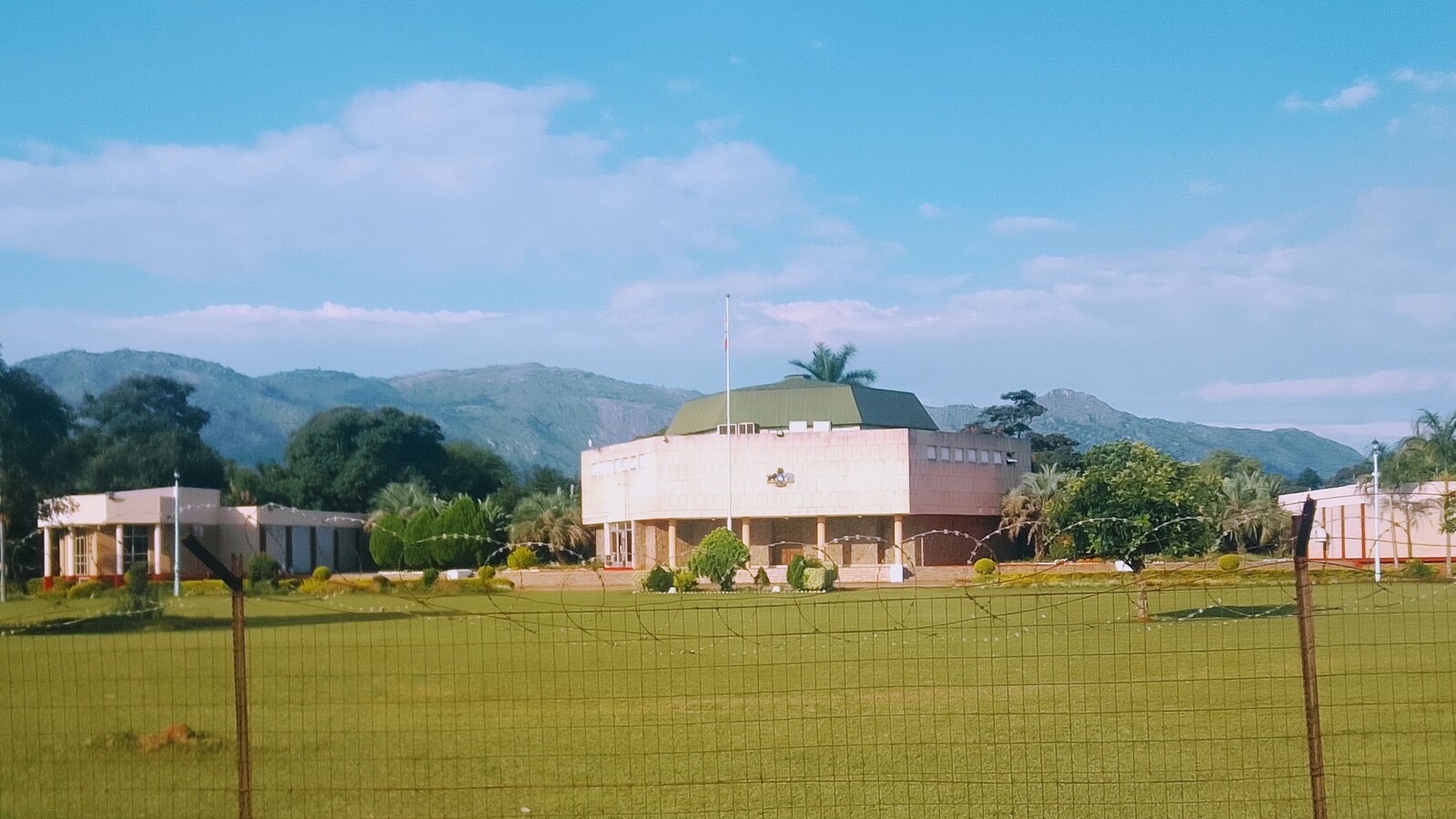 The Parliament of Eswatini in Lobamba with green lawns and mountains behind it