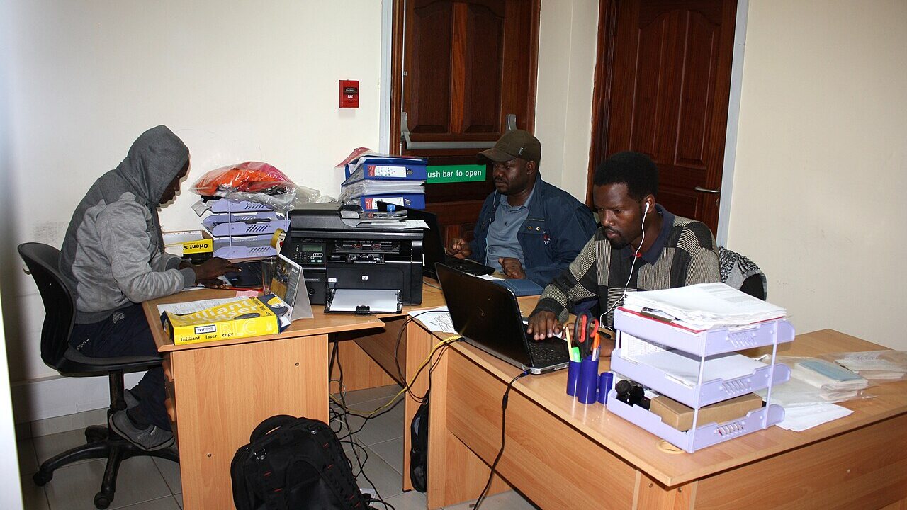 Three people working with laptops and documents in a Nairobi office in November 2017