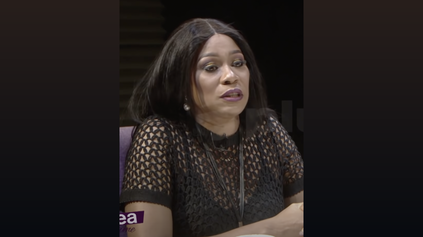 Regina Askia speaking during a 2019 Plus TV Africa interview, presented within a wide dark editorial background